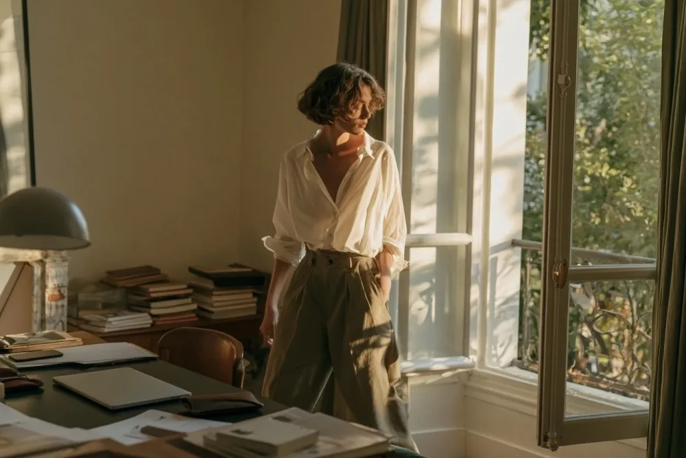 Femme s’éloignant de son bureau vers une fenêtre ouverte après une session